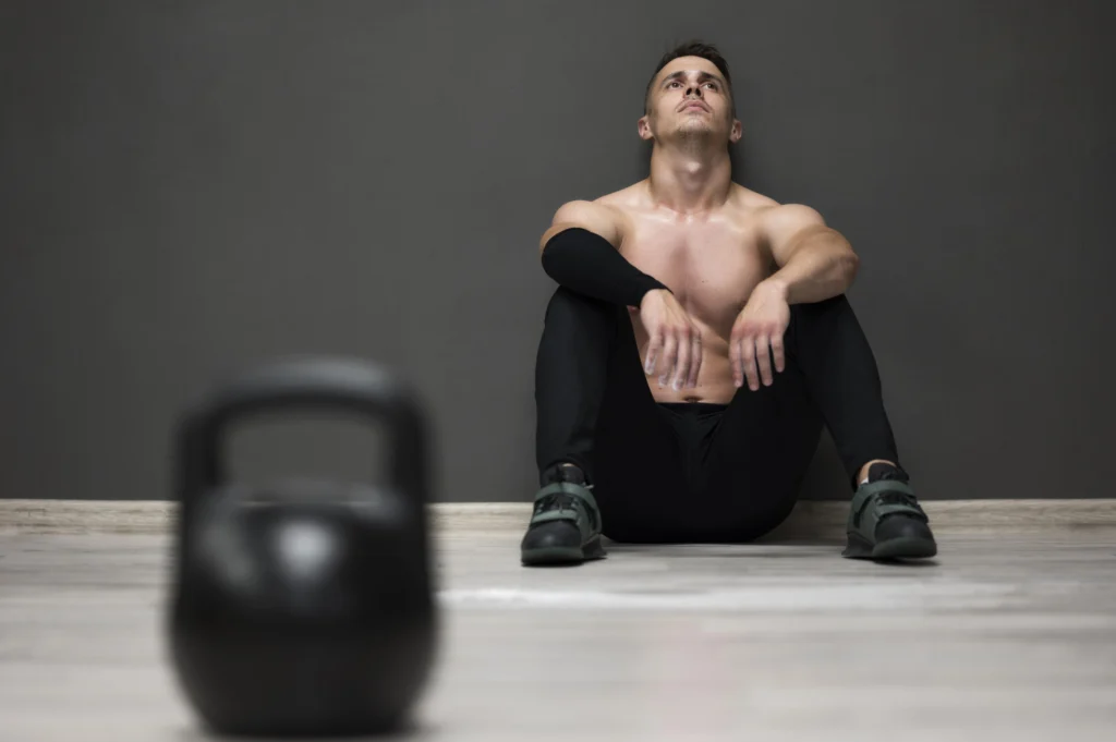 athlete sitting exhausted on gym floor after workout due to low energy