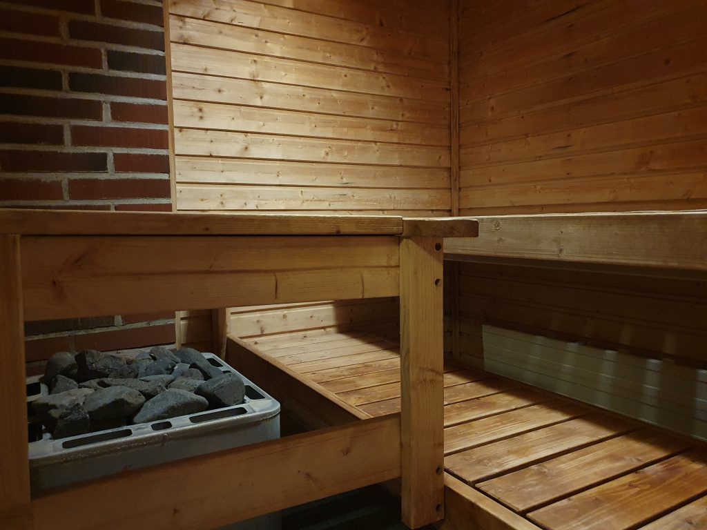 Interior of a steaming sauna with wooden benches and a warm, misty atmosphere.