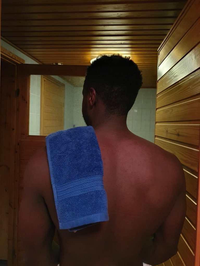 Walking into a sauna with a towel on my back.