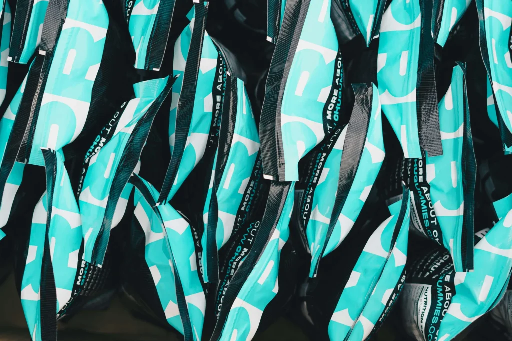 An array of crumpled pre-workout supplement bags in turquoise with bold black and white text, closely packed together, questioning the guidelines of air travel with the keyword: Can You Bring Pre-Workout on a Plane?
