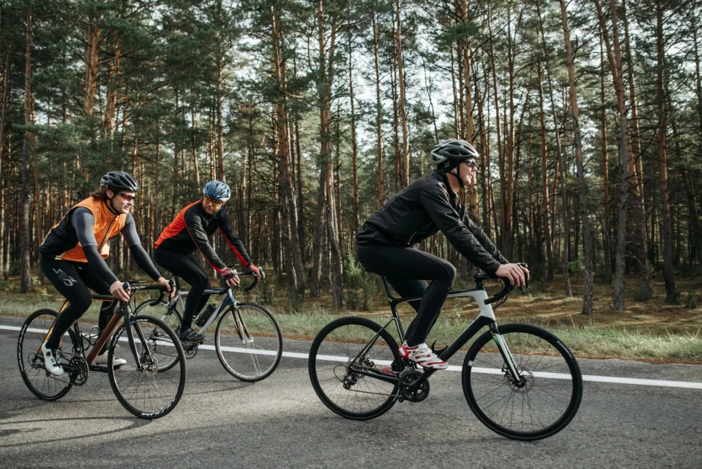 Three cyclists riding bikes through a scenic forest on a sunny day burning active calories