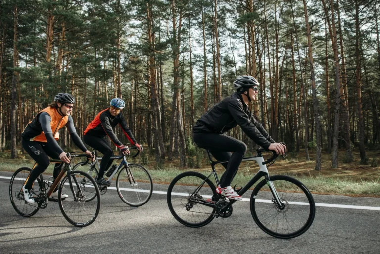 Three cyclists riding bikes through a scenic forest on a sunny day burning active calories