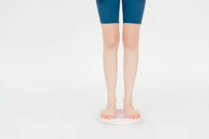 Asian BMI – woman measuring body weight on scales for health assessment