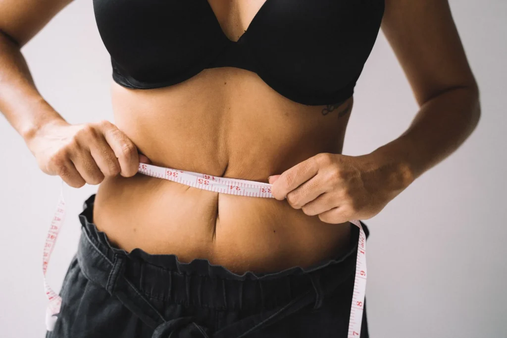 attractive waist to hip ratio – woman measuring waist with tape measure showing fitness and body composition results