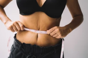 attractive waist to hip ratio – woman measuring waist with tape measure showing fitness and body composition results