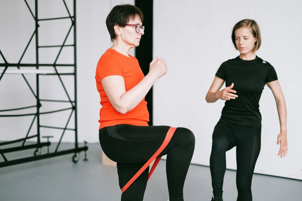women muscle mass – personal trainer guiding woman through resistance training exercise