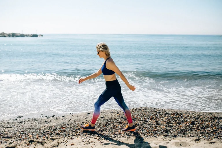 calories burned walking 5 miles – woman power walking on sunny beach in activewear