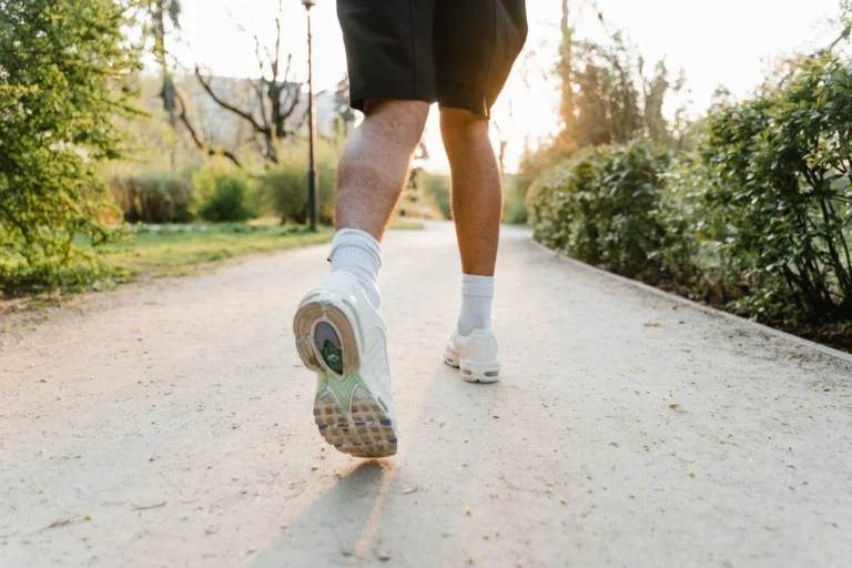 Jogger running on a park path at sunset during outdoor fitness exercise