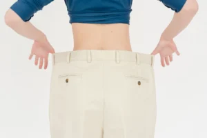 ideal waist to hip ratio – fit woman in oversized trousers showing waist and hip measurement results