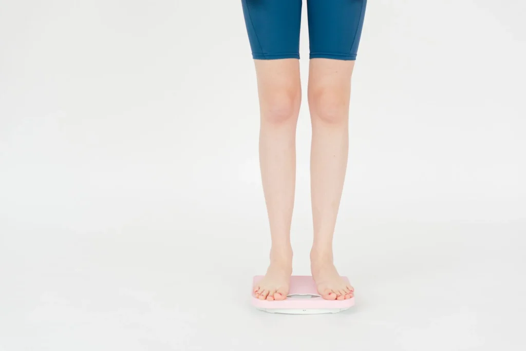 ponderal index BMI comparison – person standing on scale with height measurement for body mass assessment