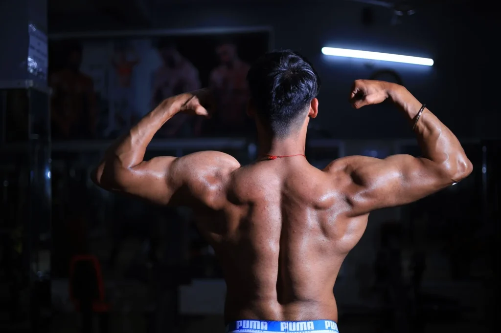 muscle mass percentage – muscular man flexing back muscles in gym demonstrating high muscle mass