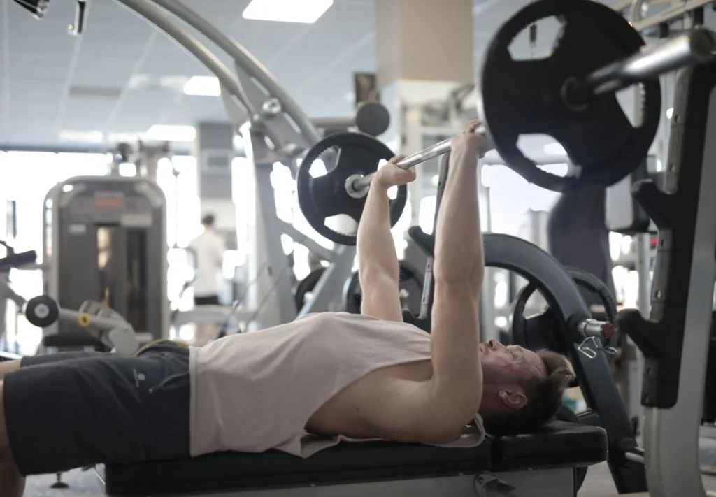bench press vs push-ups – person performing barbell bench press in a gym for strength and muscle building