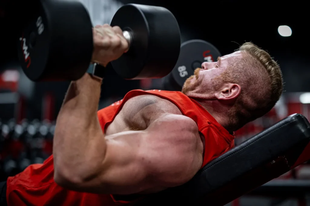 Man performing a dumbbell chest press on a bench in the gym