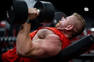 Man performing a dumbbell chest press on a bench in the gym