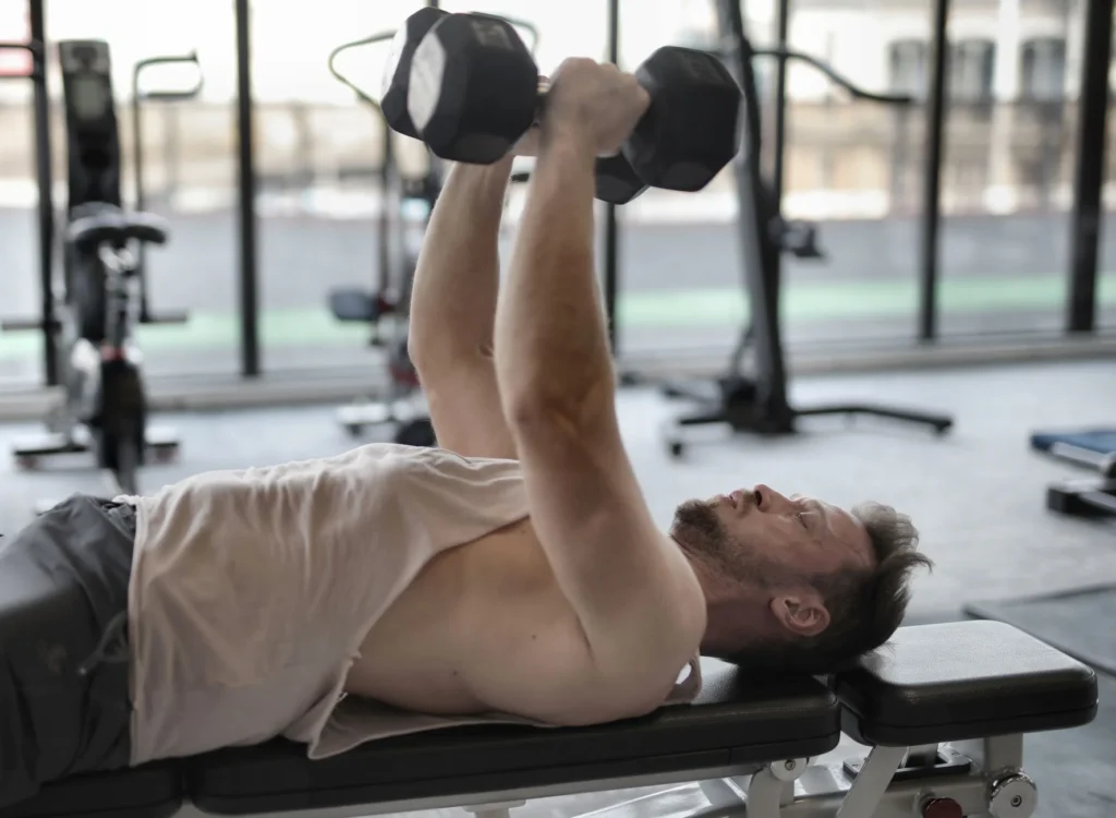 Man performing a dumbbell bench press on a gym bench for strength training
