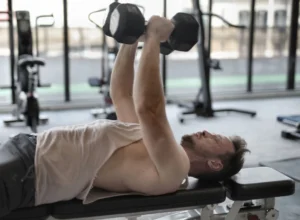 Man performing a dumbbell bench press on a gym bench for strength training