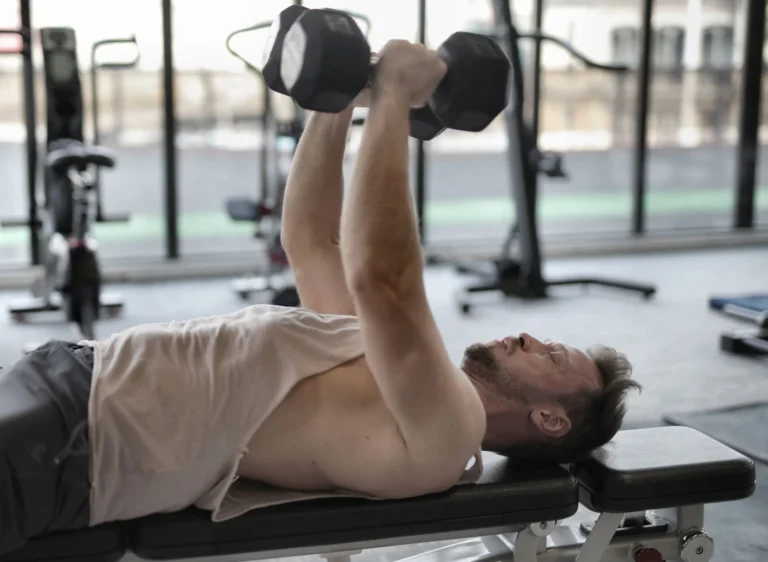 Man performing a dumbbell bench press on a gym bench for strength training