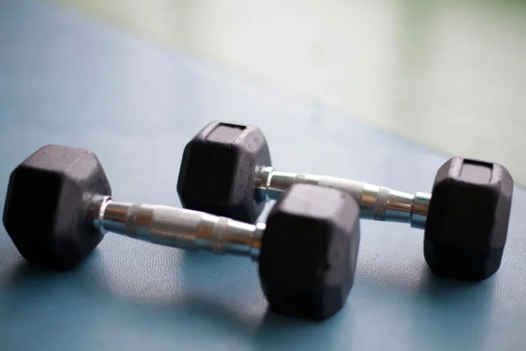 Two black hex dumbbells on a gym floor for choosing the right dumbbell weight