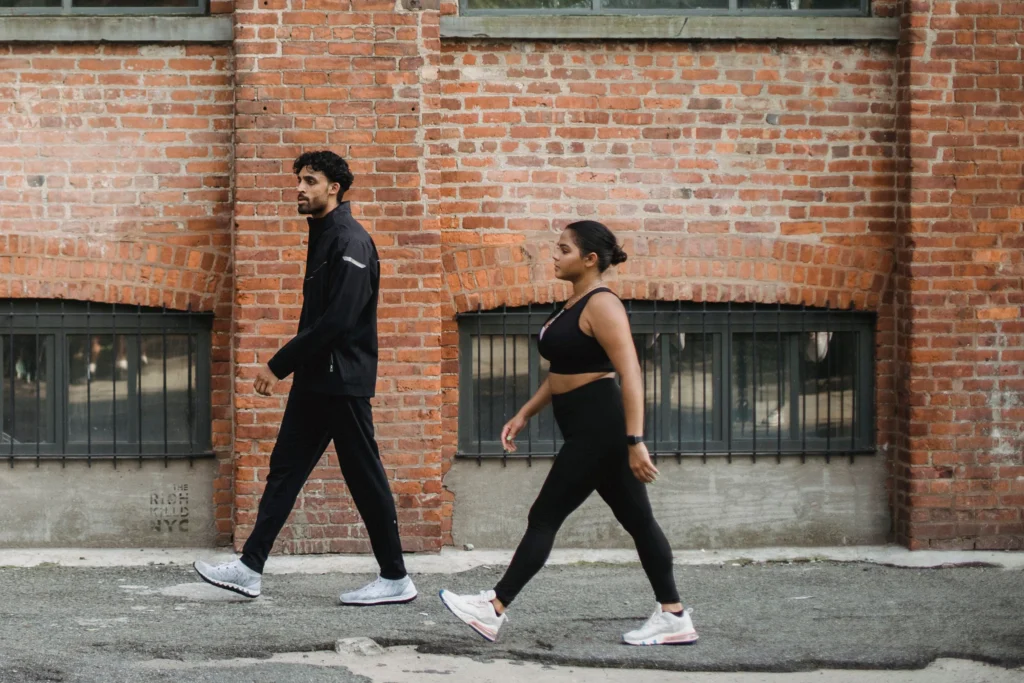 walking steps daily – man and woman walking briskly in sportswear for fitness