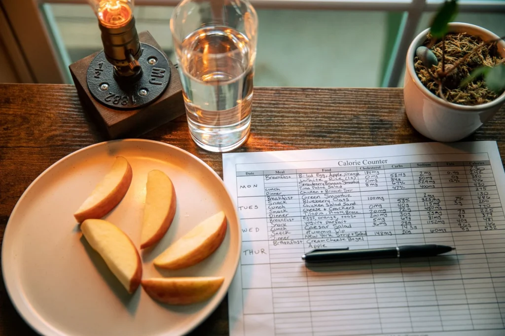 Personalized meal plan – calorie chart and healthy food on a table for goal-based nutrition