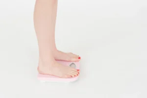 Woman standing on a scale measuring her weight for tracking