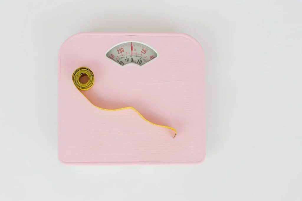 Weight tracker chart – floor scale and measuring tape used to monitor body weight progress