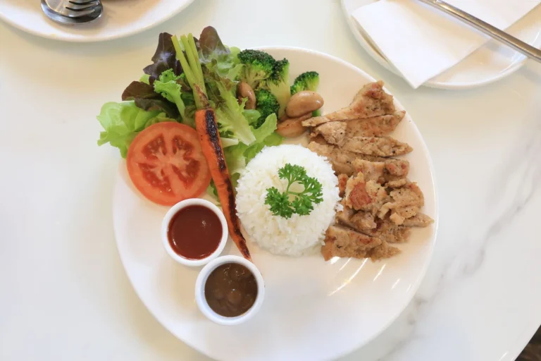 Vibrant plate of grilled chicken, rice, and vegetables, an example of a muscle recovery meal