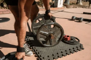 Man adjusting weight plates on a barbell, adding load as part of a progressive overload plan