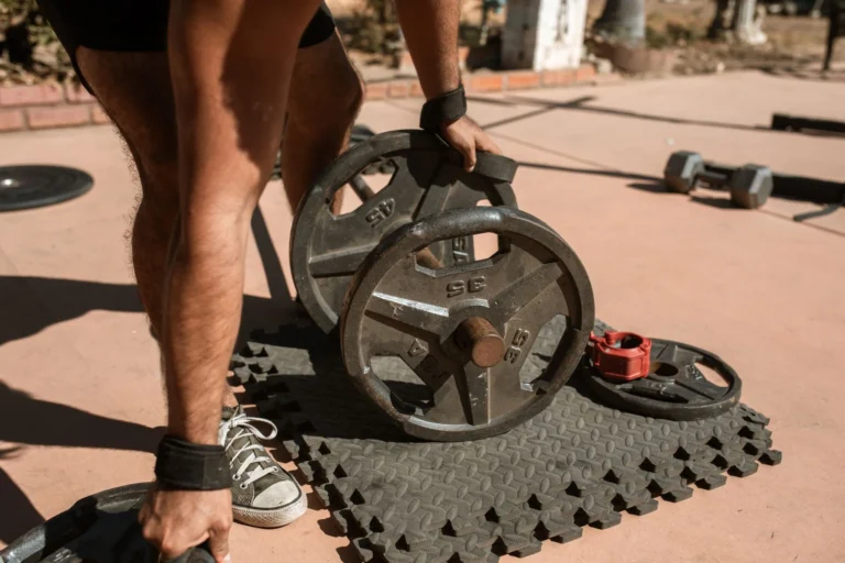 Man adjusting weight plates on a barbell, adding load as part of a progressive overload plan