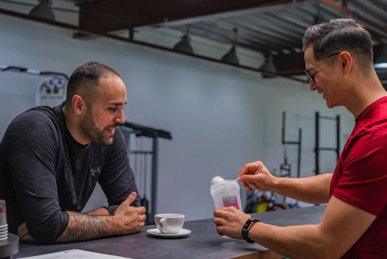 Two people preparing a protein smoothie together after a workout, illustrating whether you should drink a protein shake on rest days