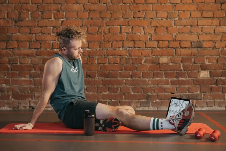 Man resting on a mat in the gym after a workout, illustrating how many rest days a week you actually need for recovery