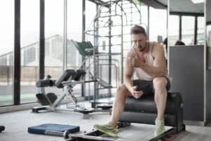 Tired athlete sitting on a bench resting after an intense weightlifting workout