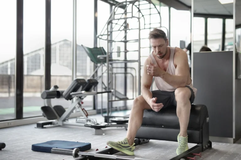 Tired athlete sitting on a bench resting after an intense weightlifting workout