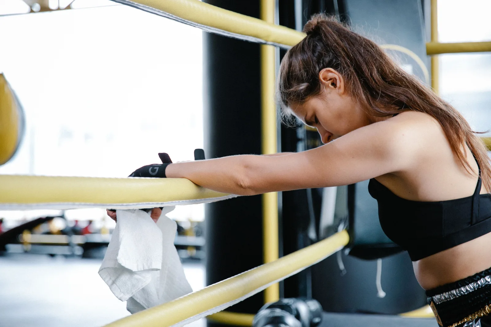 Exhausted woman resting her arms on gym equipment after a workout