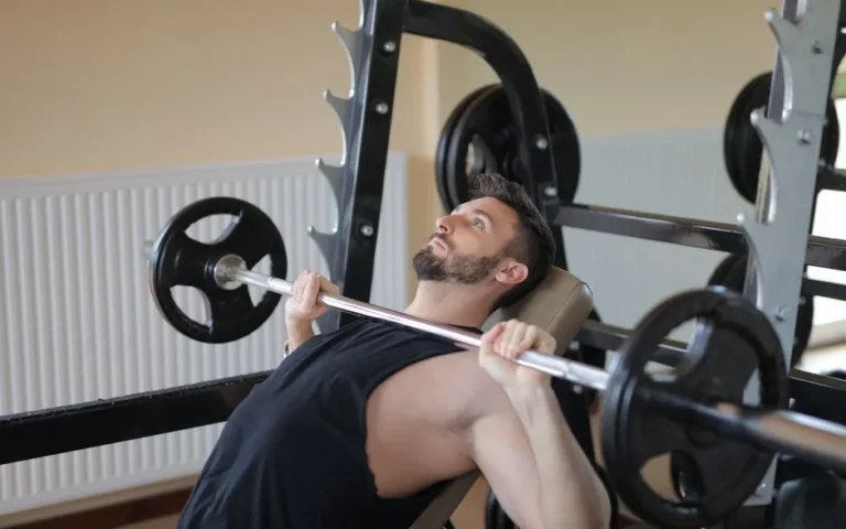 Man straining to complete a barbell bench press rep while training to failure