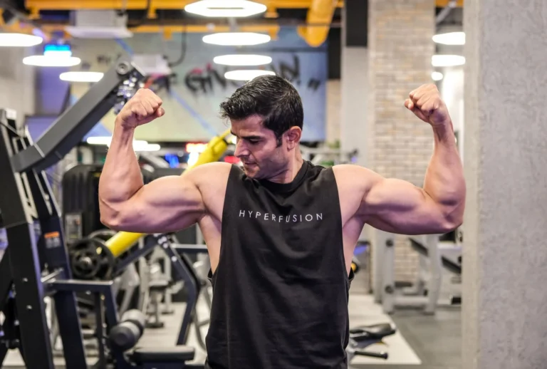 Muscular man flexing his biceps in a gym, illustrating muscle memory after training