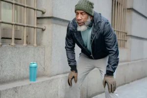 Man leaning forward with hands on knees, exhausted after pushing too hard during a workout