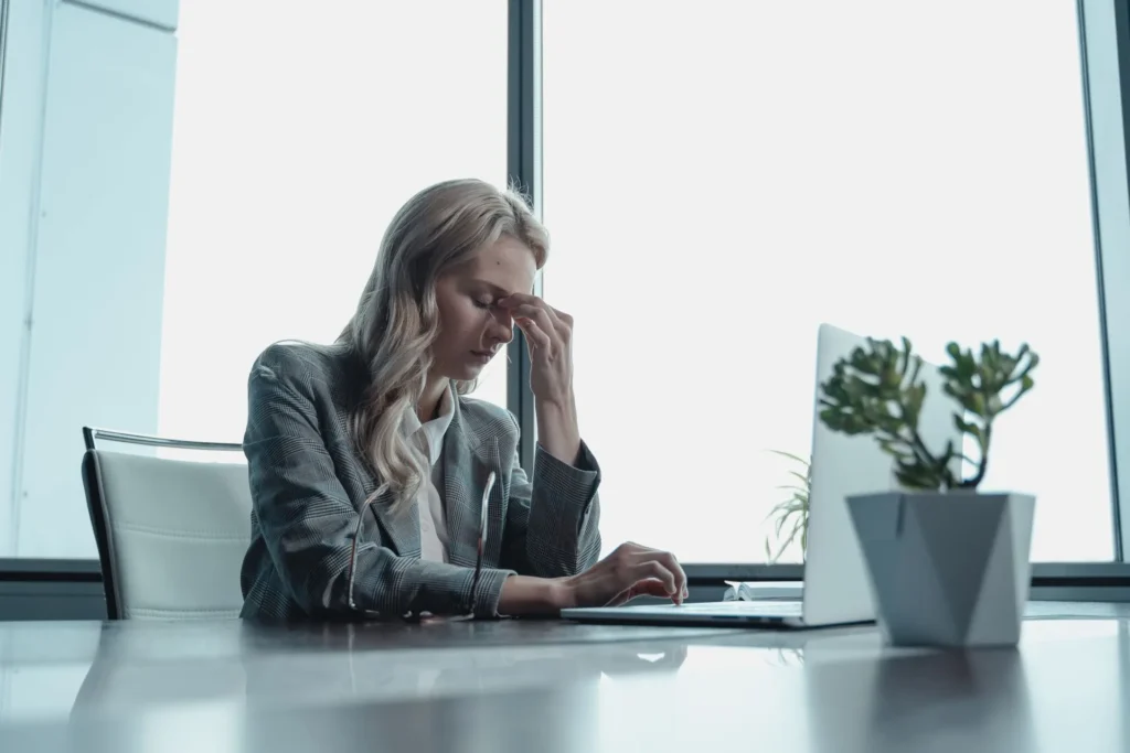 Woman pinching the bridge of her nose at her desk, stressed at work
