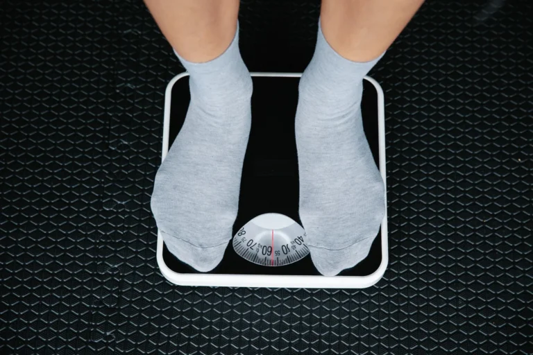 Feet in grey socks standing on an analogue bathroom scale